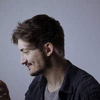 极速电竞设备评测编辑手持多台手机对比不同机型帧率表现的场景照，背景为霓虹蓝光带